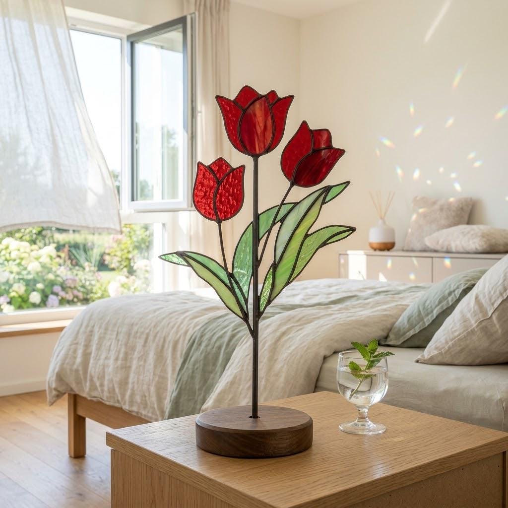 Handmade 3D red tulip stained glass flower standing on a solid walnut wood base, casting vibrant colored shadows in hard sunlight, perfect for Mother's Day gift and botanical cottagecore desk decor.