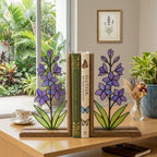 Handmade stained glass purple larkspur flower bookends on premium wood bases casting colorful shadows, beautiful July birth flower botanical shelf decor.