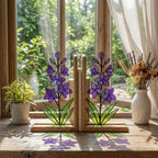 Handmade stained glass purple larkspur flower bookends on premium wood bases casting colorful shadows, beautiful July birth flower botanical shelf decor.