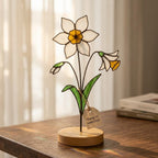 Handcrafted flat stained glass birth month flowers standing on personalized wooden bases, casting colorful light reflections. Perfect Mother's Day or birthday gift.