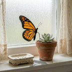 Handmade stained glass monarch butterfly plant stake displayed in a green ceramic planter