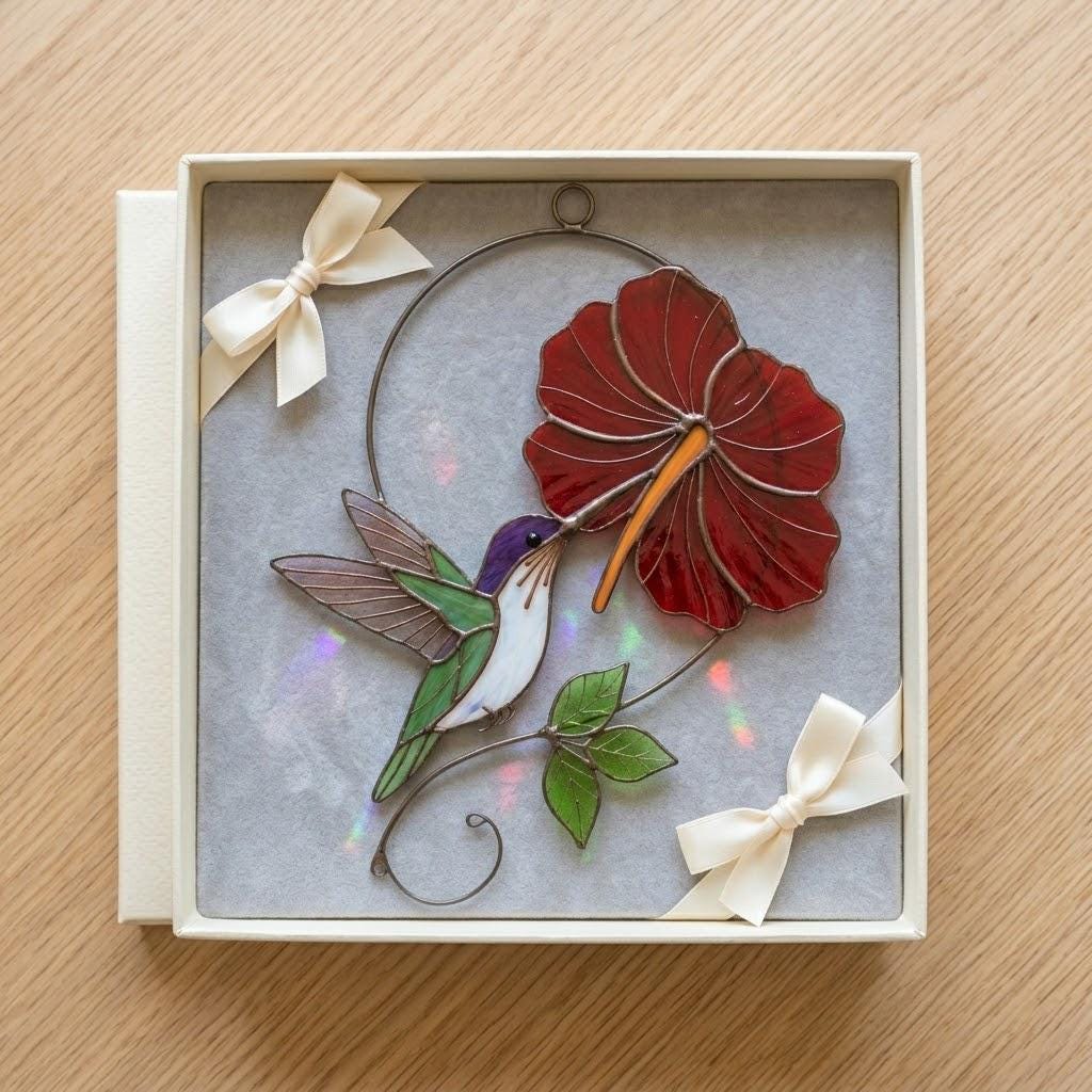 Handmade hummingbird and red hibiscus flower stained glass suncatcher casting vibrant colored shadows, perfect tropical botanical decor and memorial gift for mom.