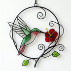 Handcrafted stained glass hummingbird and floral suncatchers in a circular metal hoop, casting colored shadows, packaged in a luxury wooden gift box for Mother's Day.