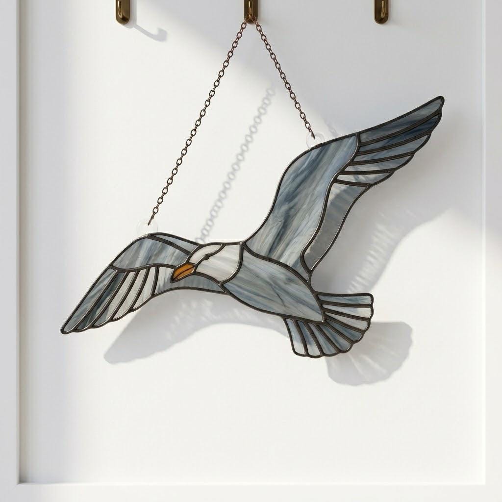 Handcrafted wispy stained glass flying seagull suncatcher casting shadows, perfect coastal beach house decor and nautical ocean lover gift.