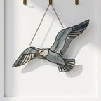 Handcrafted wispy stained glass flying seagull suncatcher casting shadows, perfect coastal beach house decor and nautical ocean lover gift.
