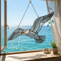 Handcrafted wispy stained glass flying seagull suncatcher casting shadows, perfect coastal beach house decor and nautical ocean lover gift.