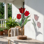 Handmade 3D red tulip stained glass flower standing on a solid walnut wood base, casting vibrant colored shadows in hard sunlight, perfect for Mother's Day gift and botanical cottagecore desk decor.