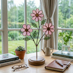 Handcrafted pink cosmos stained glass flower tree standing on a custom personalized engraved wooden base casting colored shadows, perfect October birth flower or Mother's Day desk decor gift.