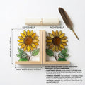 Yellow stained glass sunflower bookends with green leaves on a natural wood base holding books, catching spring sunlight on a desk.